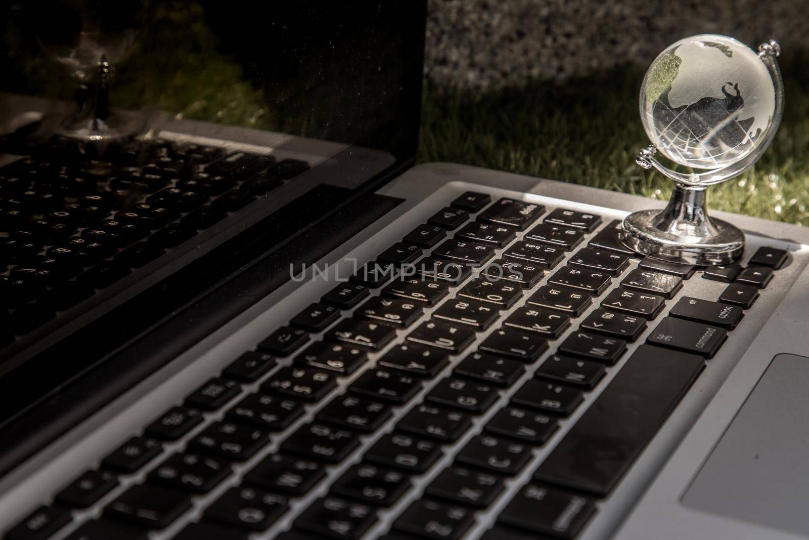 Glass crystal globe on Laptop keyboard. Concept for global communication and business. Selective focus.