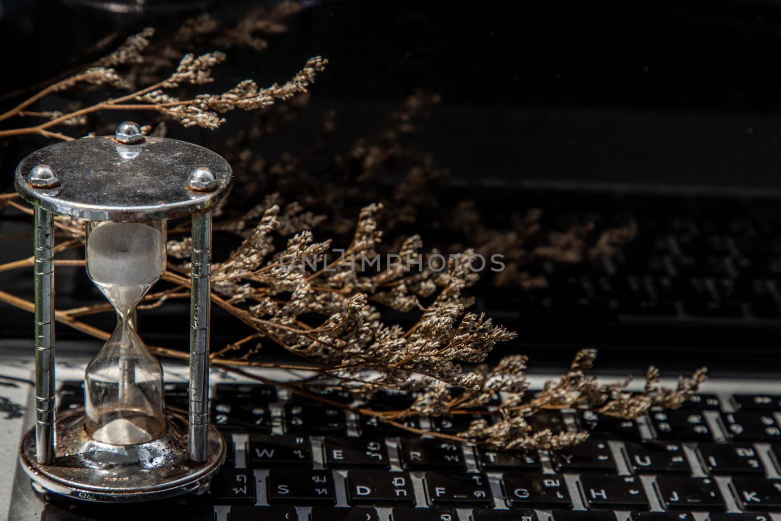 Hourglass on laptop keyboard. Time management concept and Countdown to deadline. Selective focus.
