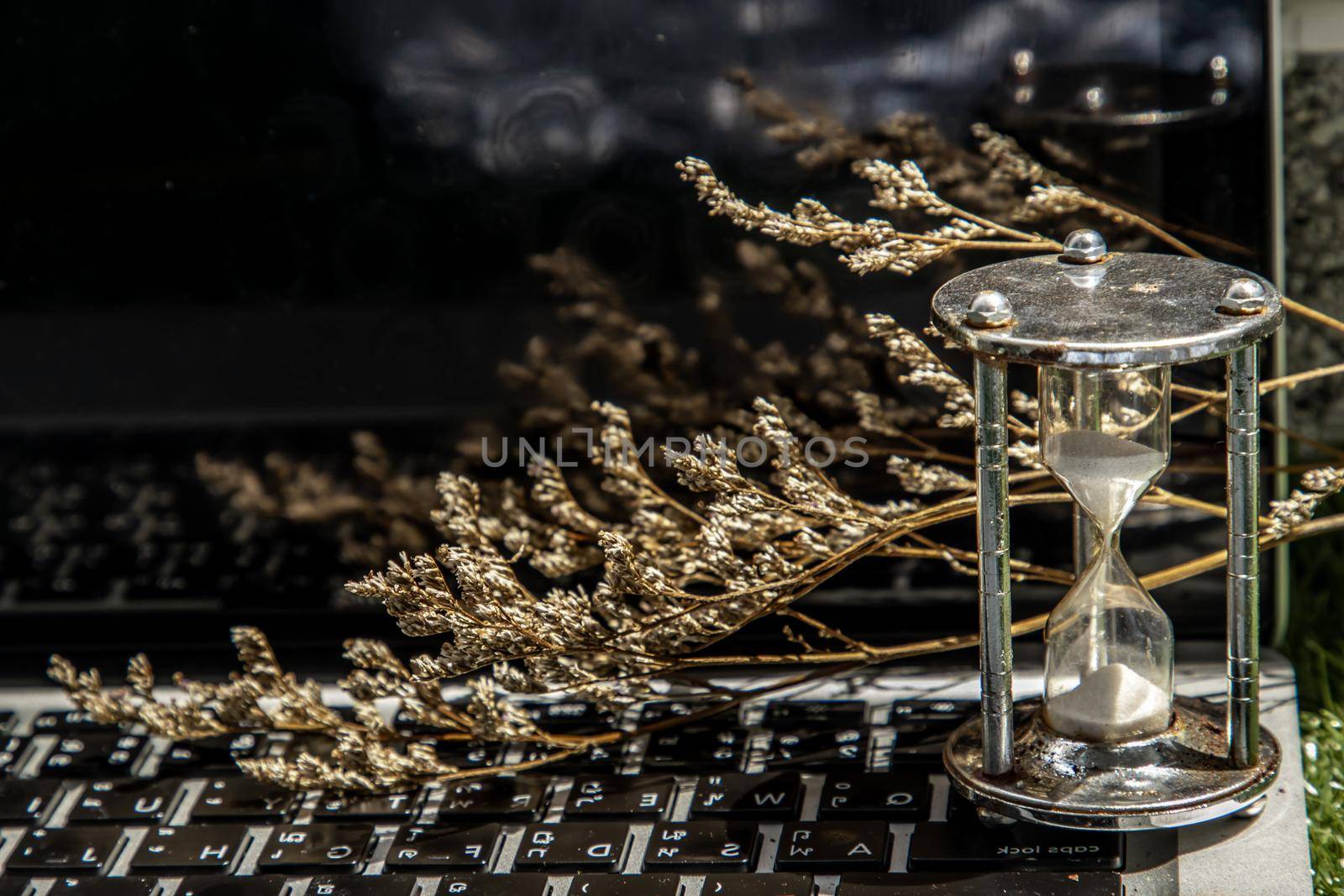 Hourglass on laptop keyboard. Time management concept and Countdown to deadline. Selective focus.