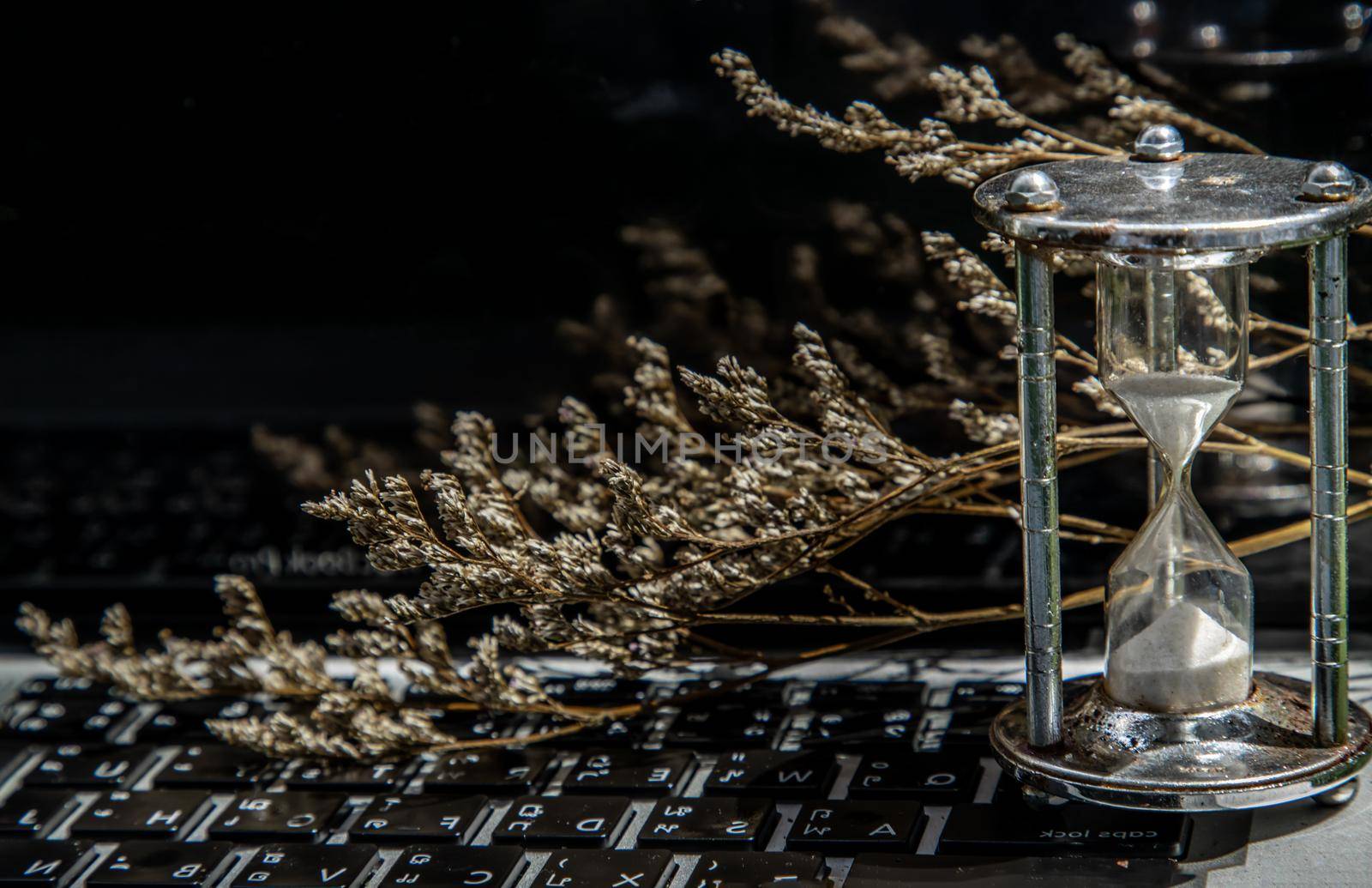 Hourglass on laptop keyboard. Time management concept and Countdown to deadline. Selective focus.