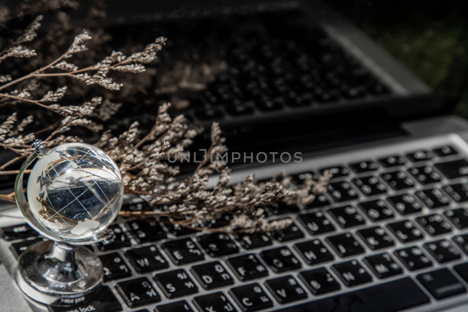 Glass crystal globe on Laptop keyboard. Concept for global communication and business. Selective focus.