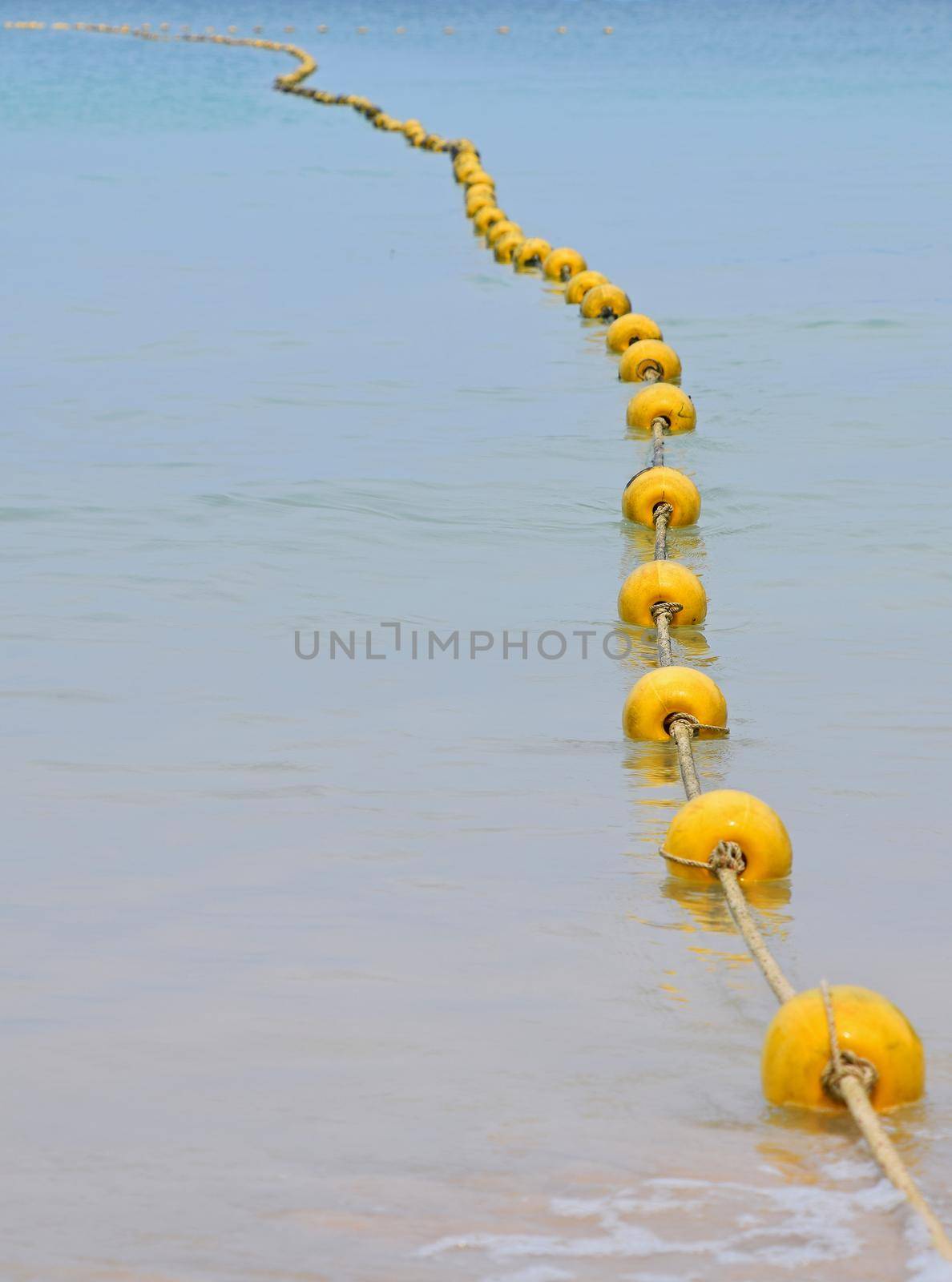 Chain of yellow buoys in blue sea water by BreakingTheWalls