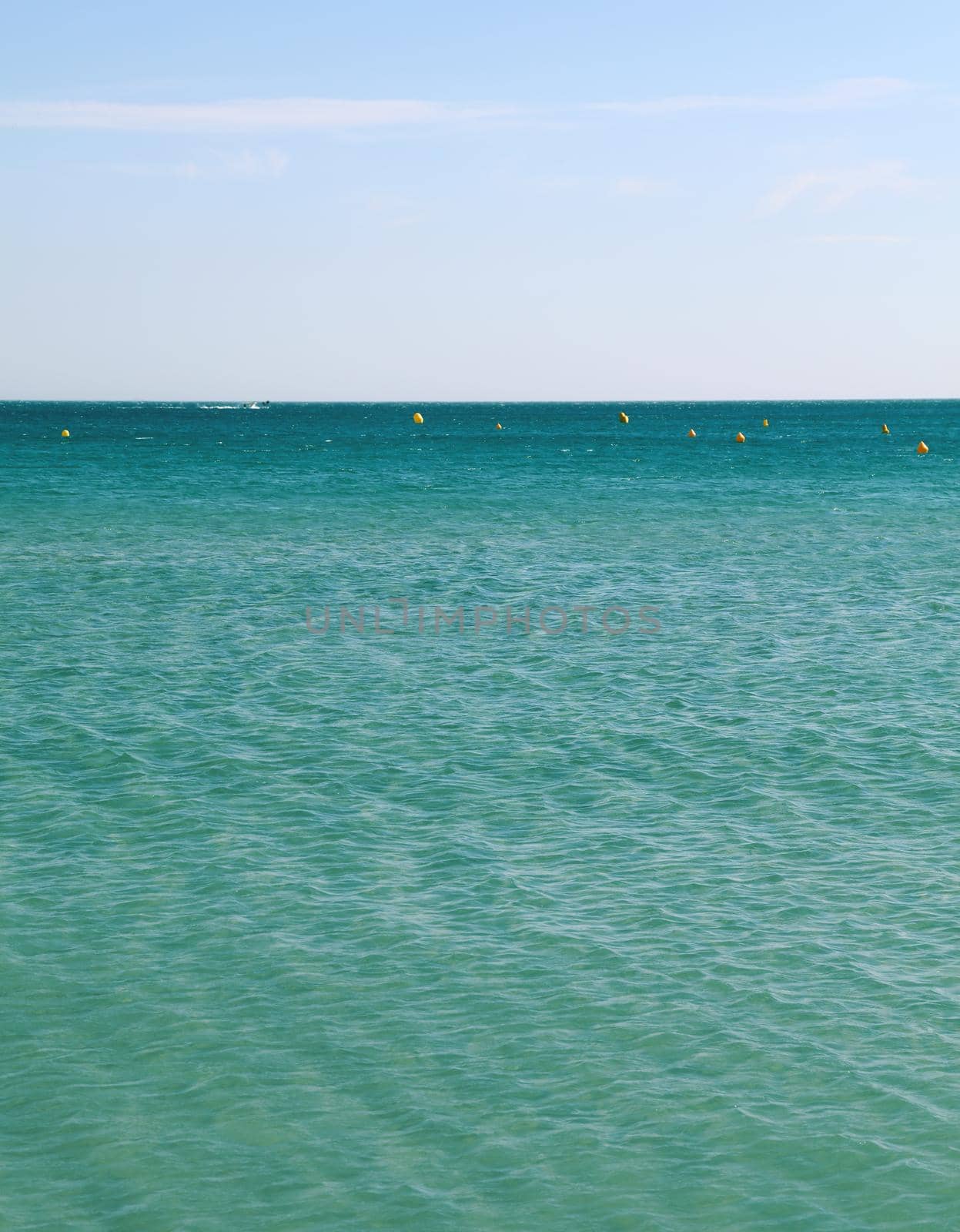 Tranquil seascape with calm turquoise sea water ripples and waves under clear day blue sky, high angle view