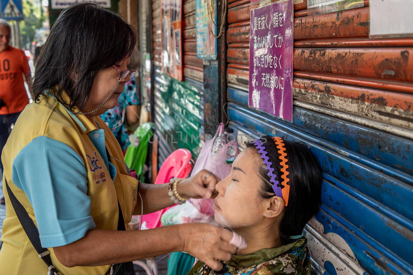 Bangkok, thailand - Feb 16, 2020 : Yaowarat street merchant service customer face hair removal beauty by yarn. Ancient chinese - style hair removal, Chinese traditional “ Mang Ming “ style.