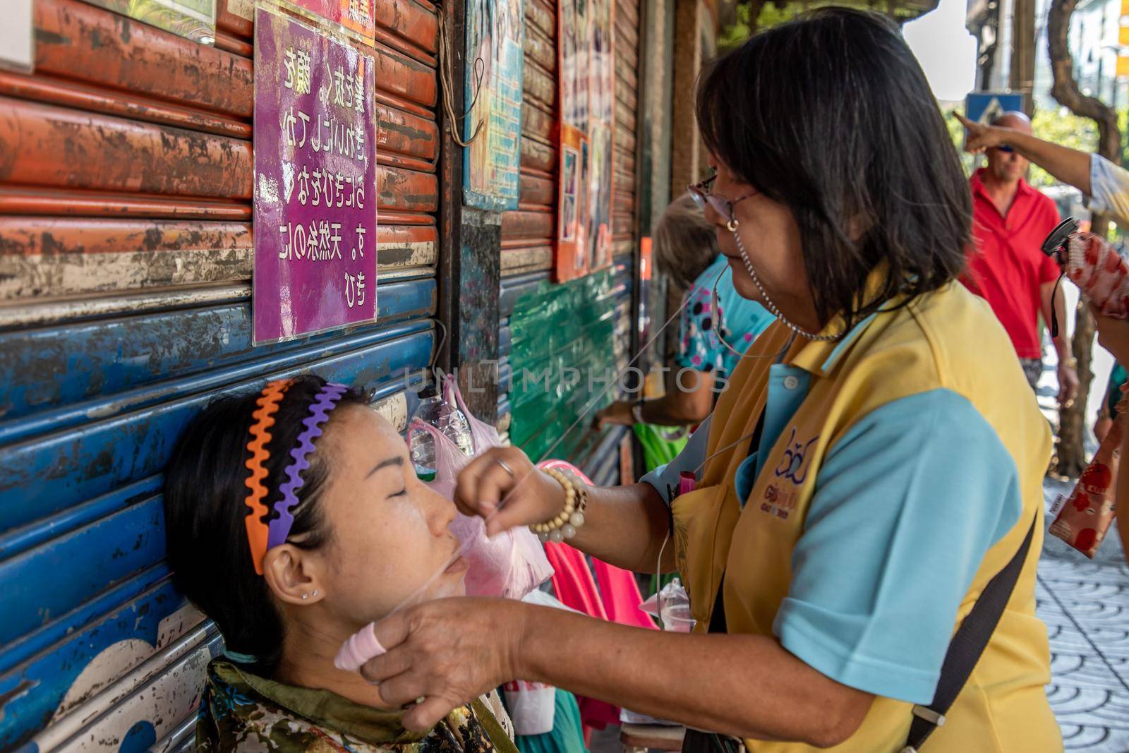 Bangkok, thailand - Feb 16, 2020 : Yaowarat street merchant service customer face hair removal beauty by yarn. Ancient chinese - style hair removal, Chinese traditional “ Mang Ming “ style.