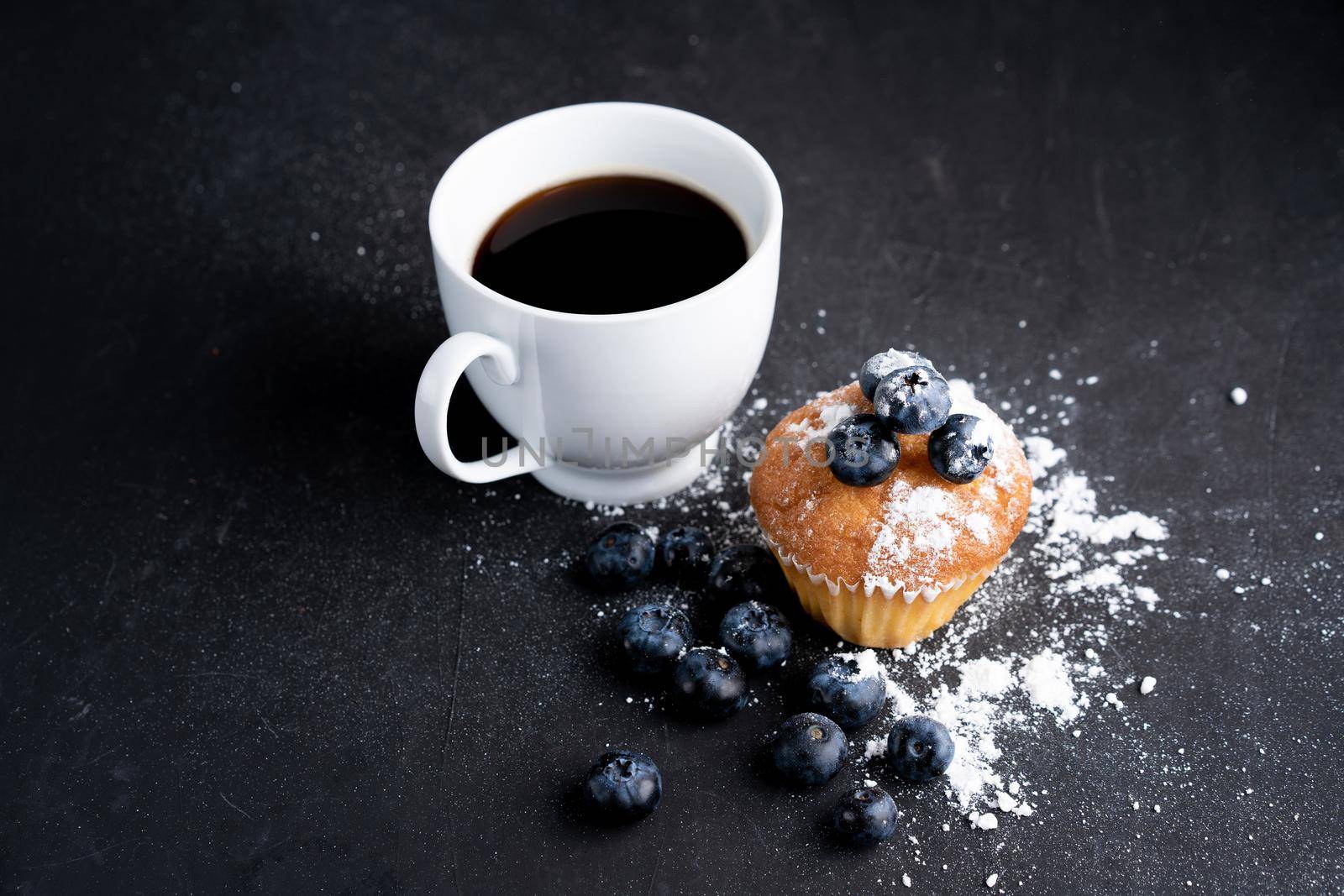Blueberry antioxidant organic superfood and sweet muffin with cup of coffe Concept for healthy eating and dieting nutrition Top view on dark black background