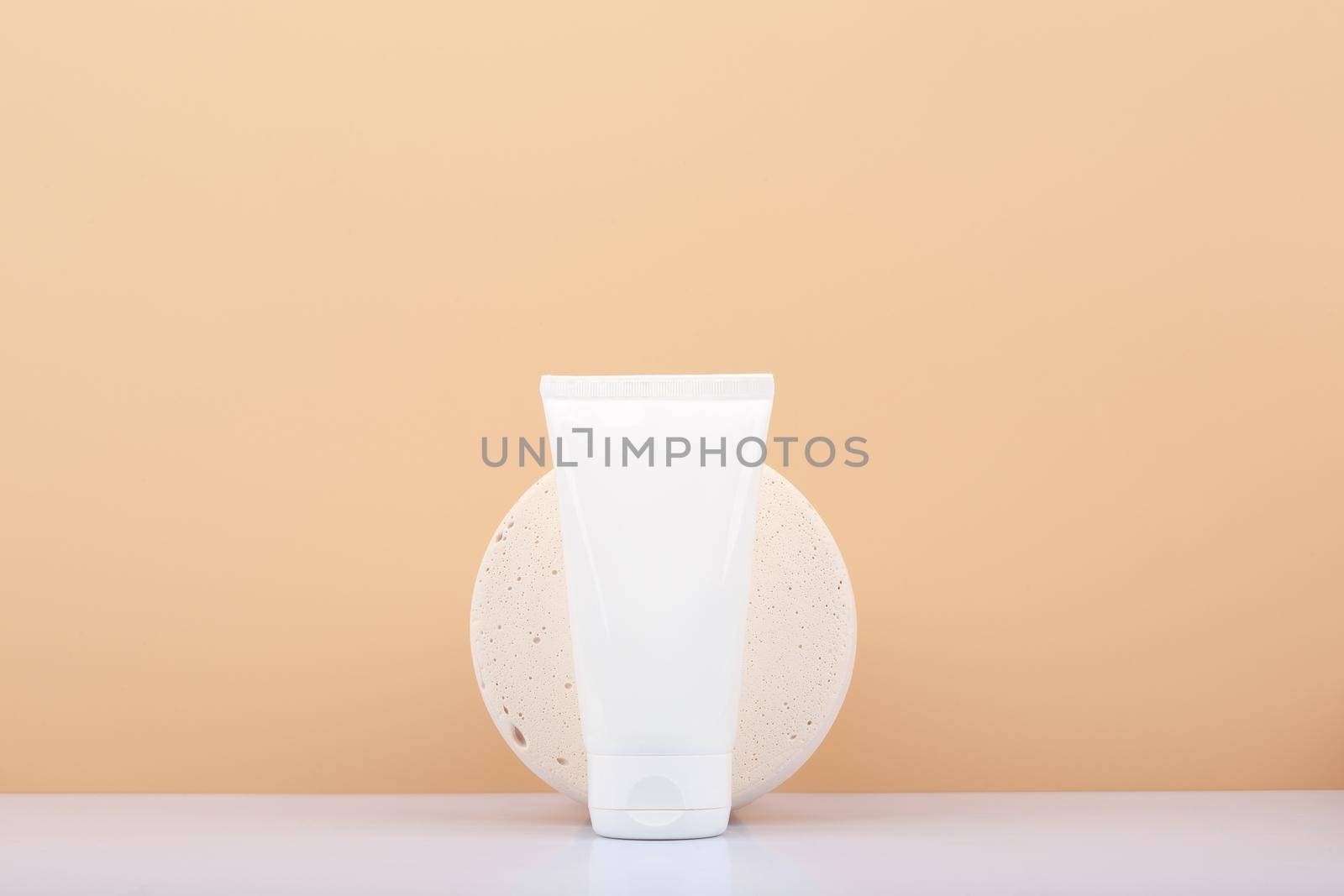 White cream tube against beige background with copy space. Concept of beauty products for skin care. Skin cream, mask scrub or exfoliation product