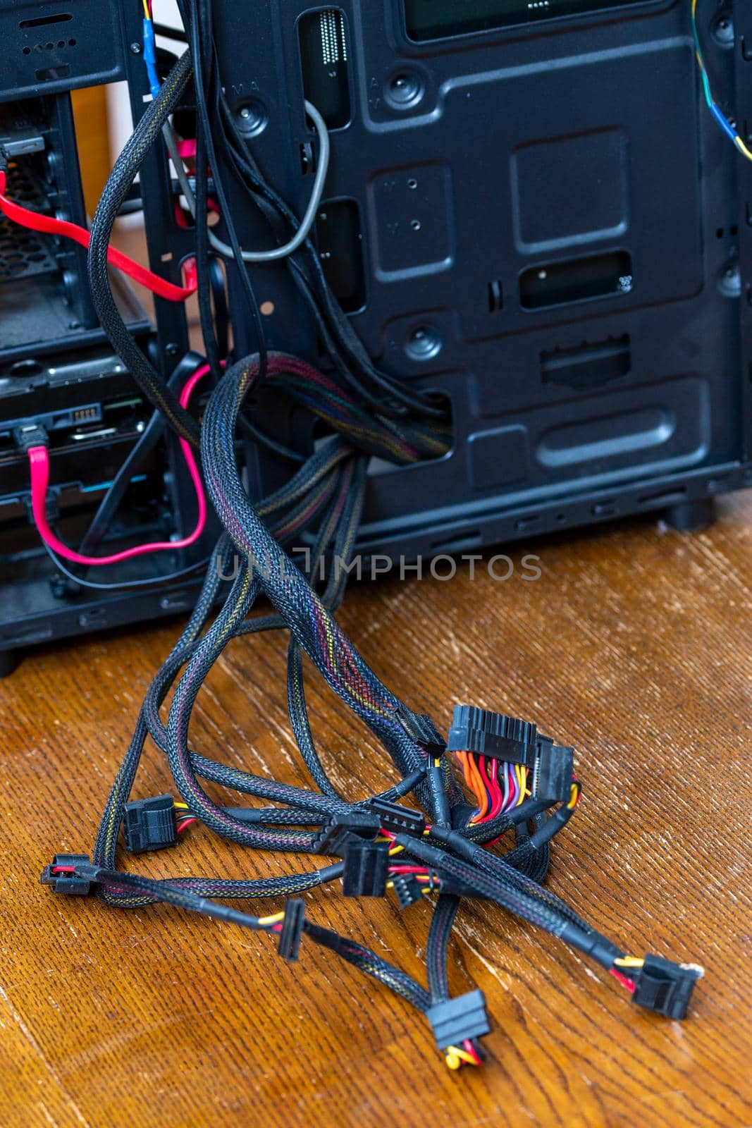 bunch of computer power supply wires sticking out from opened black pc case - close-up with selective focus.