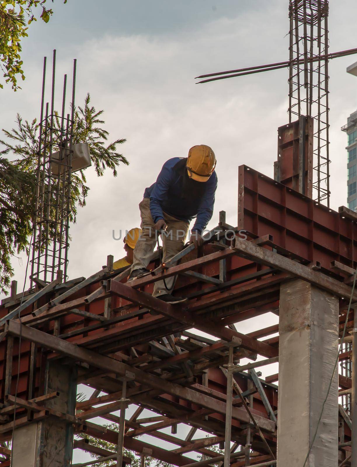 Construction Worker Welding soldering metal girders and Sparks in a Structure high above at the Construction site. Selective focus.