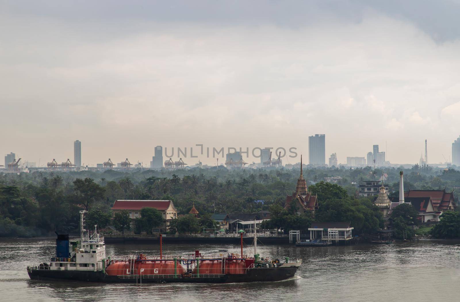 Bangkok, thailand - Oct 03, 2020 : Gas LPG tanker sailing in Chao Phraya river and through the front of Bang Krachao Nok Temple Pier. Focus and blur.