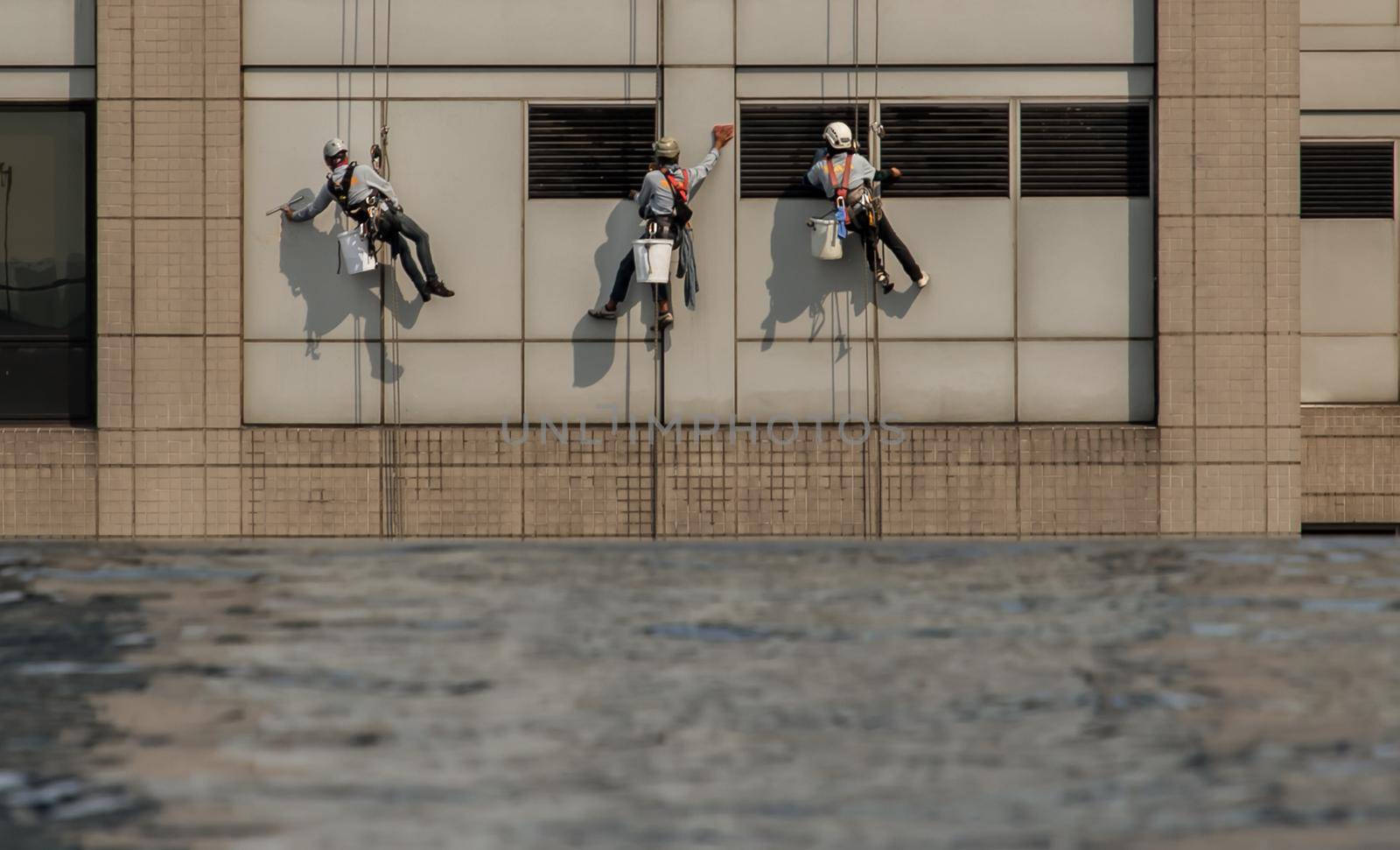 Group of workers cleaning windows service on high rise office building with reflection from swimming pool. Selective focus.