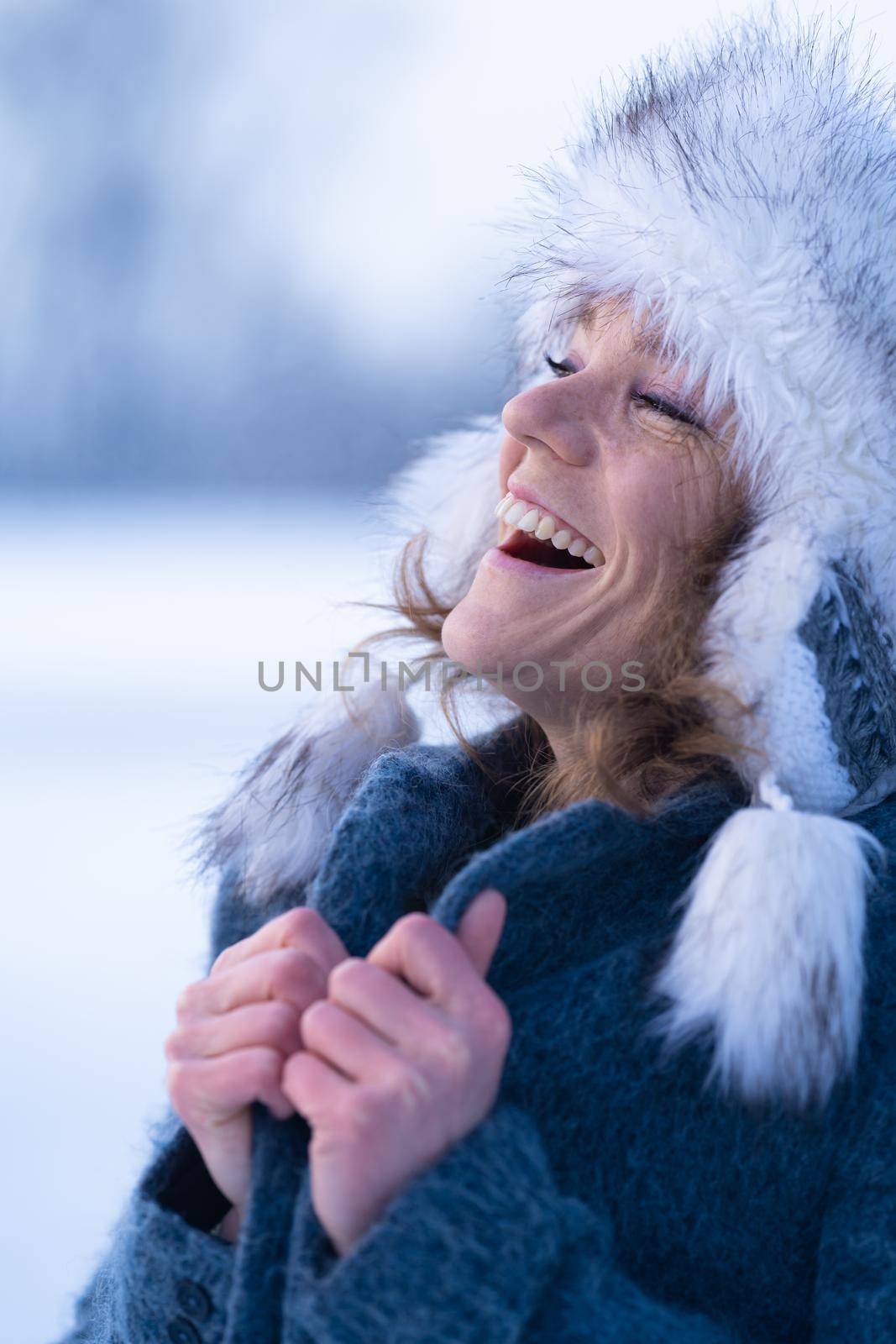 Young attractive woman happy with the falling snow in winter nature.