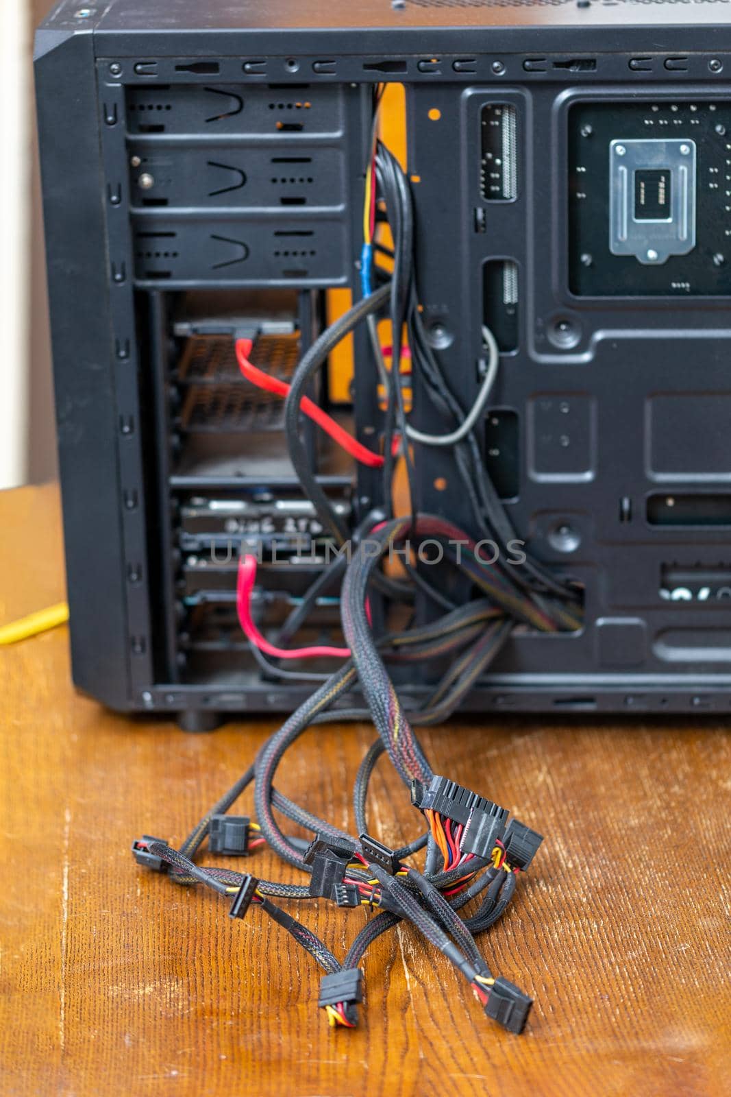 bunch of computer power supply wires sticking out from opened black pc case - close-up with selective focus.