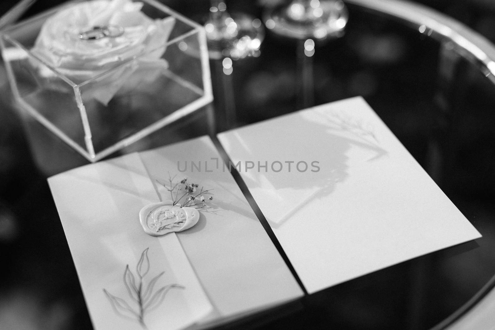 wedding invitation in a blue envelope on a table with green sprigs