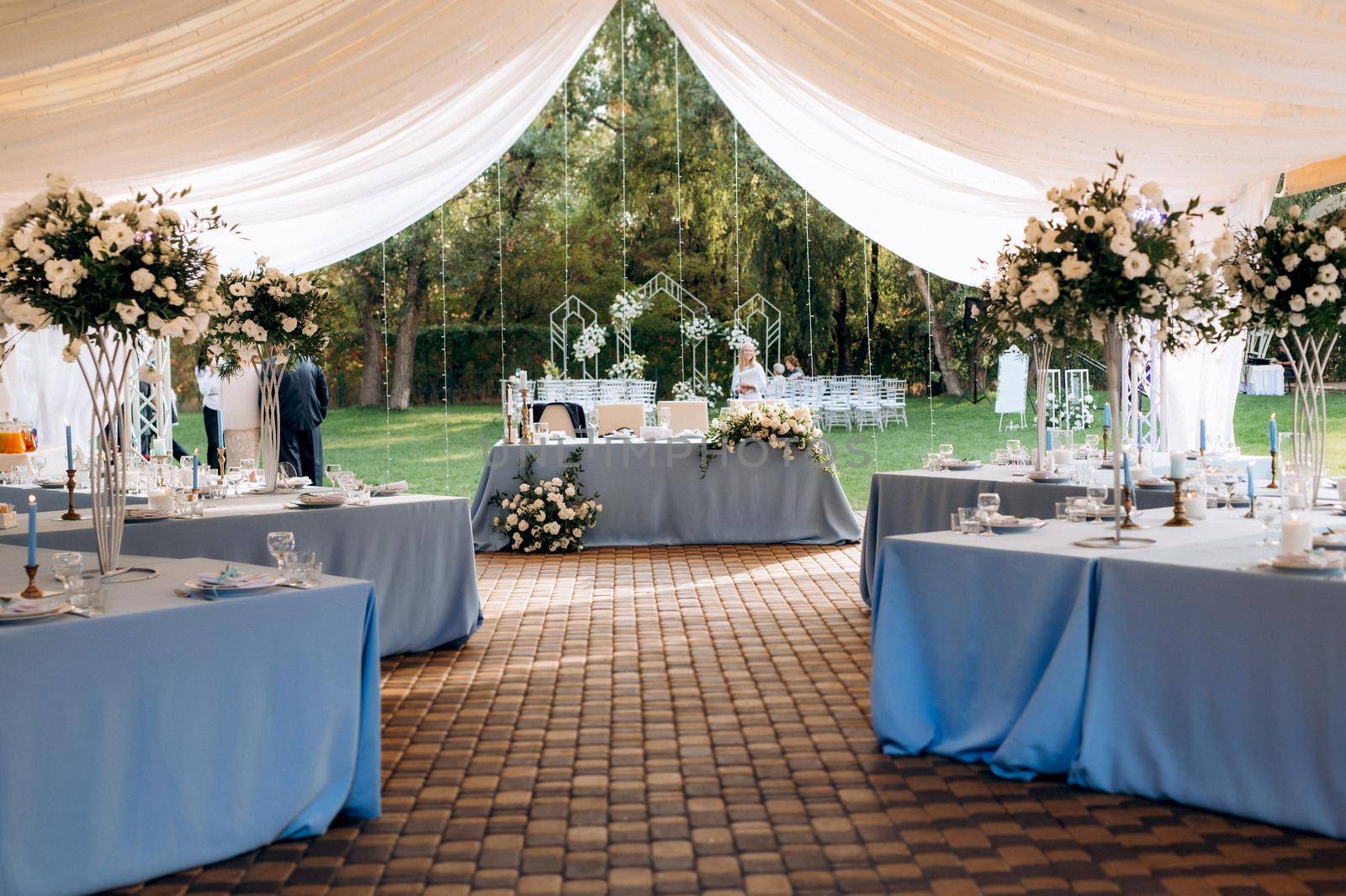 The presidium of the newlyweds in the banquet hall of the restaurant is decorated with candles and green plants, wisteria hangs from the ceiling