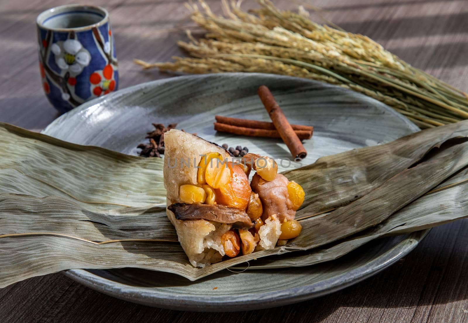 Chinese rice dumplings (Zongzi) shaped pyramidal wrapped by leaves ingredients on bowl chinese style and chopsticks served with chinese tea. Famous asian tasty handmade food in dragon boat (duan wu) festival occasion.