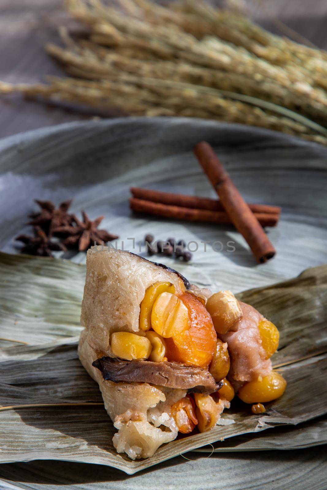 Chinese rice dumpling (Zongzi) shaped pyramidal wrapped by leaves ingredients on dried banana leaf. Famous asian tasty handmade food in dragon boat (duan wu) festival occasion.
