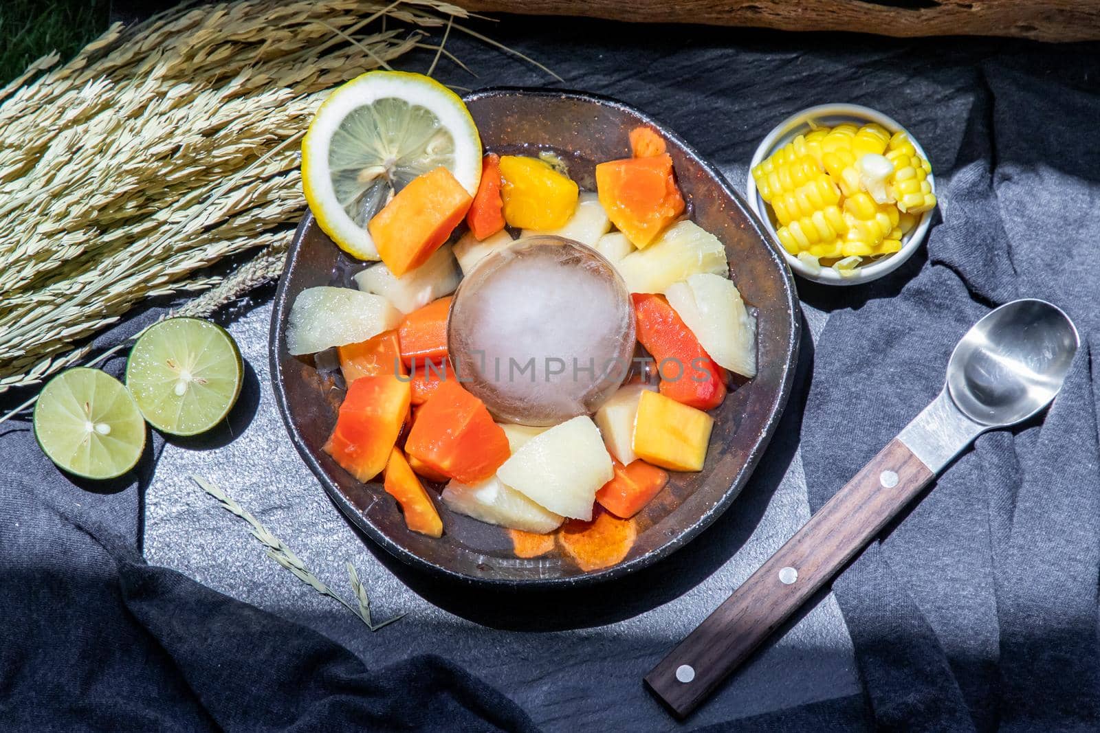 Tropical fresh fruit salad served with corn on black ceramic bowl in dark background.  Selective focus.