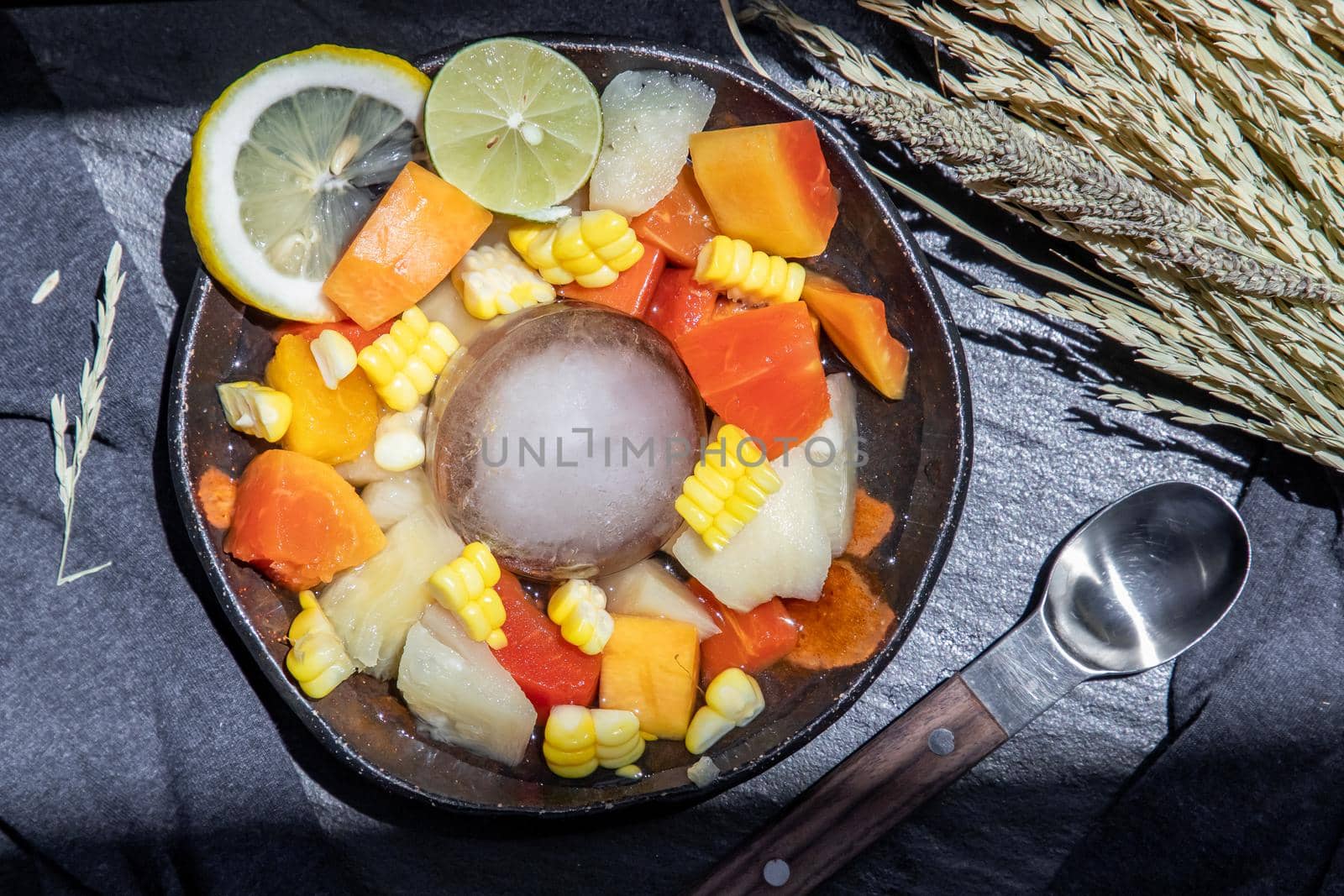 Tropical fresh fruit salad served with corn on black ceramic bowl in dark background.  Selective focus.