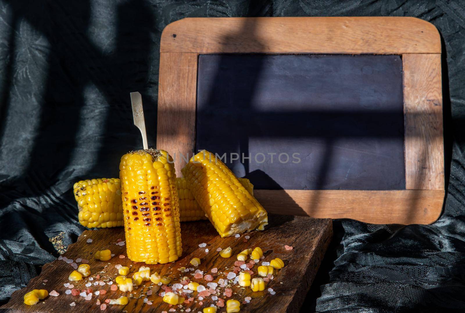 Grilled corn on the cob  on rustic wooden board   over dark background and Free space for text. Ideas for barbecue and grill parties, Barbecue concept.