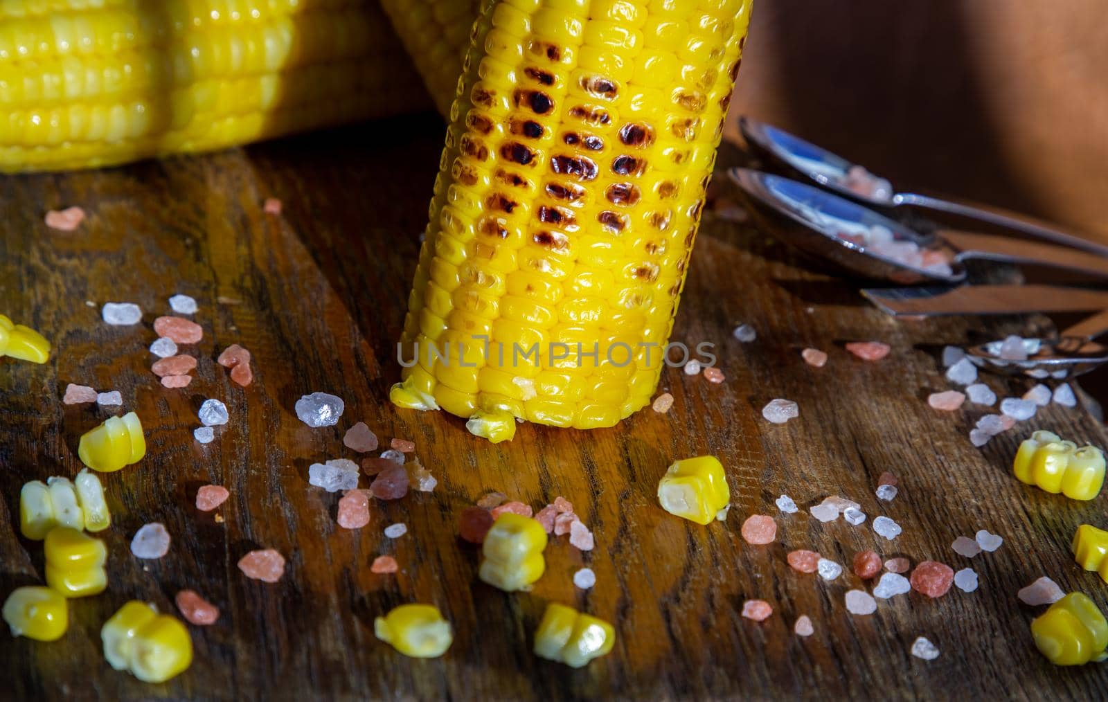 Grilled corn on the cob  on rustic wooden board over brown leather background.  by tosirikul