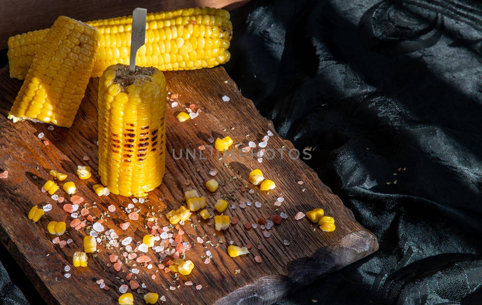 Grilled corn on the cob  on rustic wooden board  over dark background. by tosirikul
