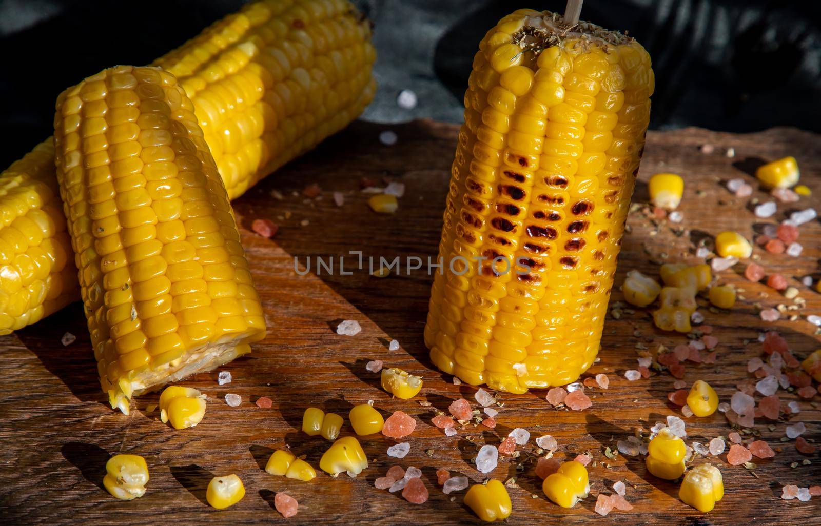 Grilled corn on the cob  on rustic wooden board   over dark background. Ideas for barbecue and grill parties, Barbecue concept.