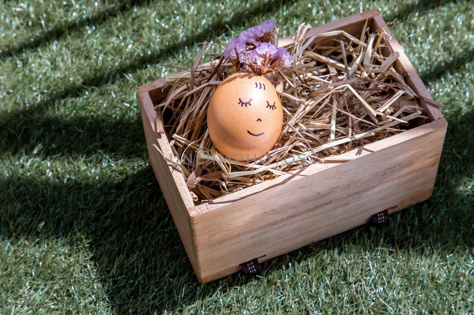 The happy egg is lying on dry straw.  Happy and relaxing concept.