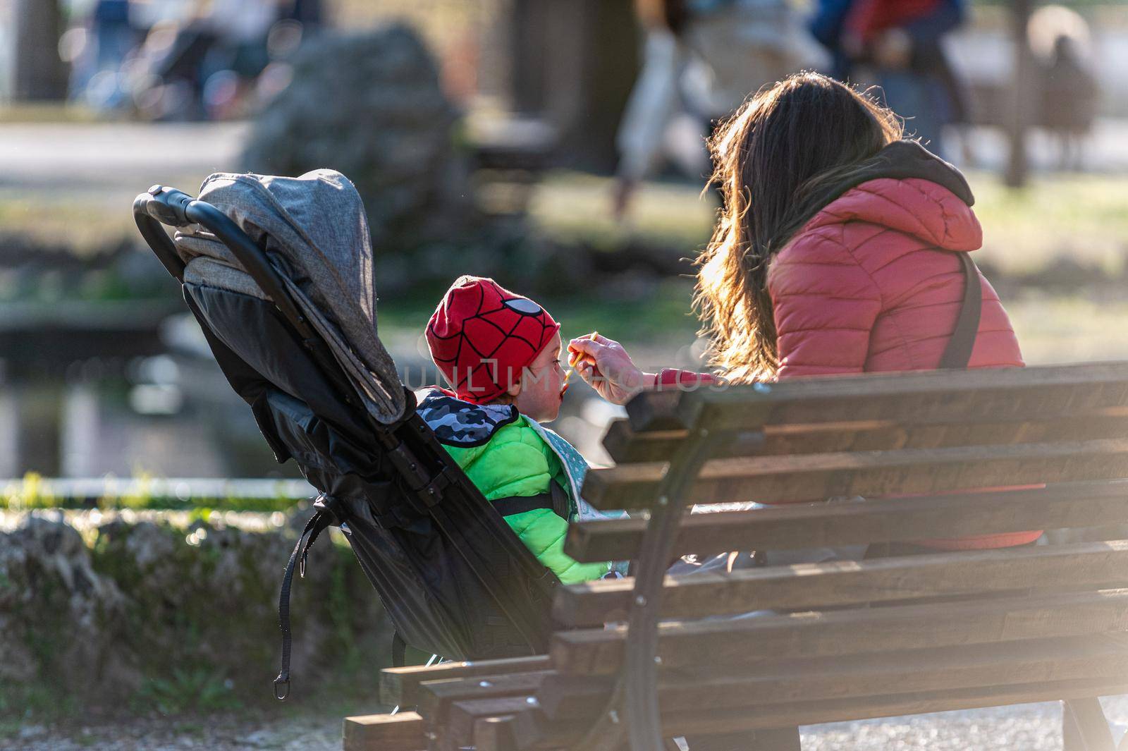 terni,italy march 25 2021:mom feeding her little son on the stroller at the park