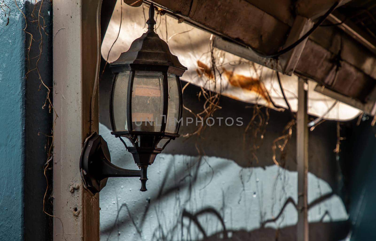 Street lamp on a steel pole at the blue brick wall.  Lamps in a narrow alley.