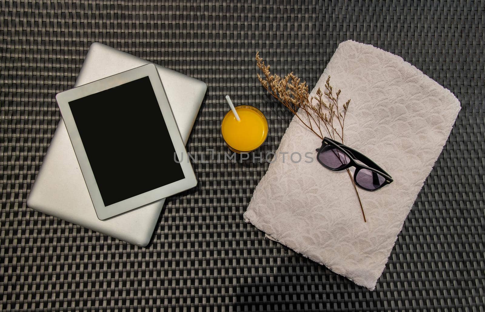 Relaxing moment by the pool. Take a break from working on laptop and tablet and enjoy the fresh orange juice under the sun for a refreshment. Outdoor swimming pool background. leisure activity.