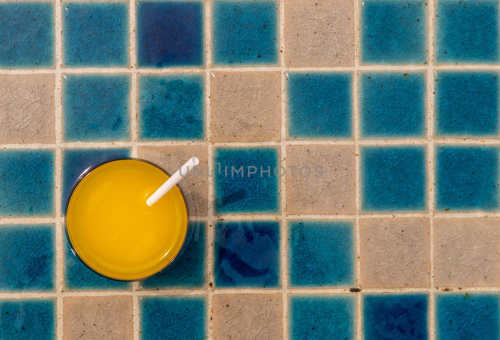 A glass of fresh orange juice for a refreshment on swiwming pool. Outdoor swimming pool background.