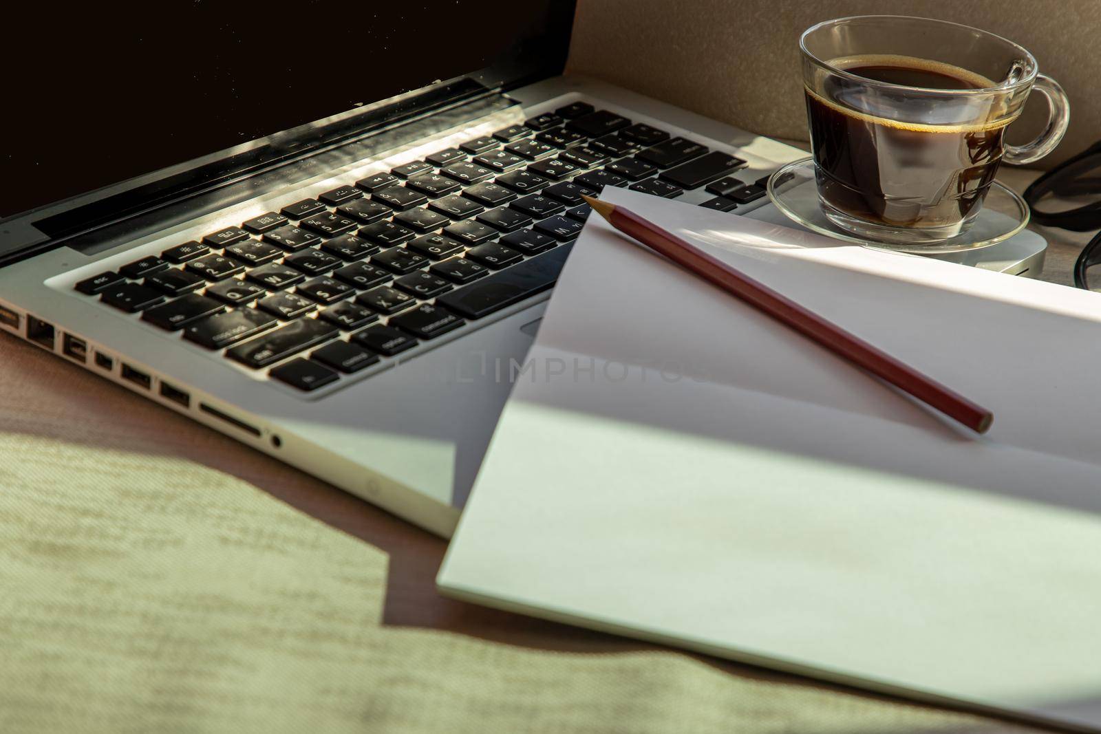 Closeup shot of Workspace with laptop, a glass of coffee notebook and pencils. Remote working concept or Business workspace.