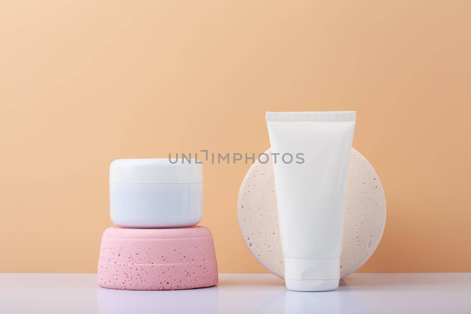 White jars with scrub and mask for face or head skin on white table against beige background. Concept of organic beauty products for skin or hair care