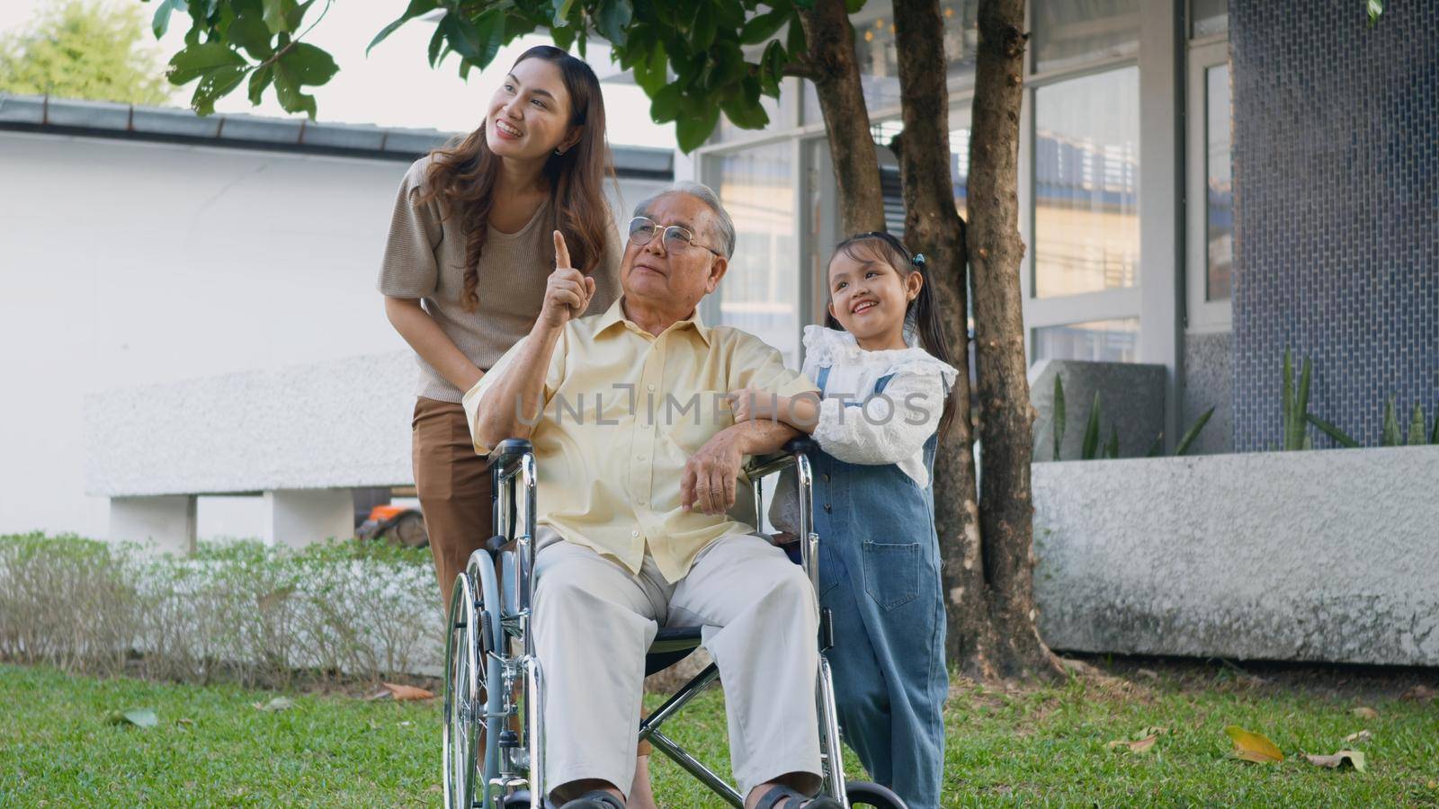 Disabled senior grandpa on wheelchair with grandchild and mother in park by Sorapop