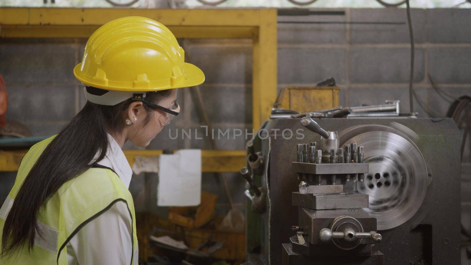 Asian professional mechanical engineer or operation woman wearing uniform goggles safety working on workshop metal lathe industrial manufacturing factory, Heavy industry lathe worker woman