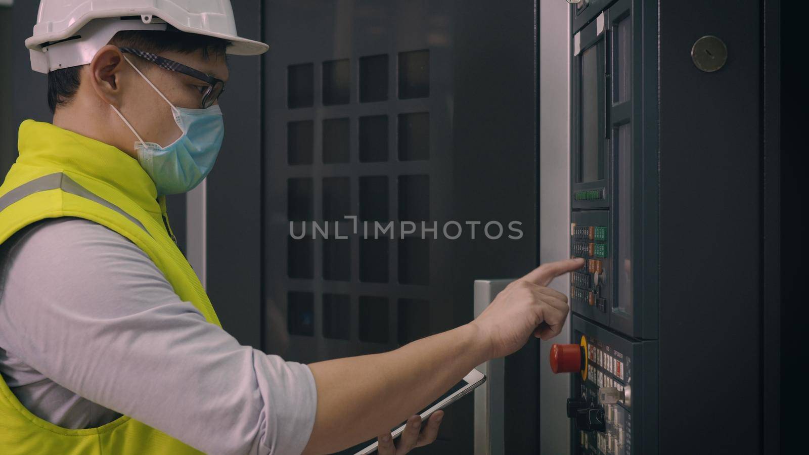 Asian factory worker man operating automated programming CNC milling control machine industry center at tool workshop manufacturing