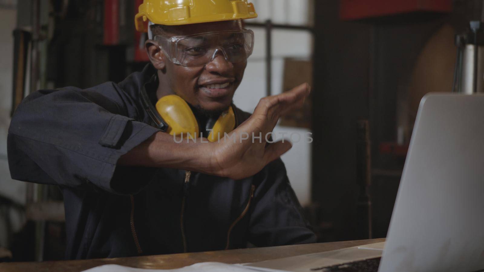 Social distance group of industrial worker, American industrial black young worker man with yellow helmet having teleconference or video conference calls meeting remotely and discussion about project