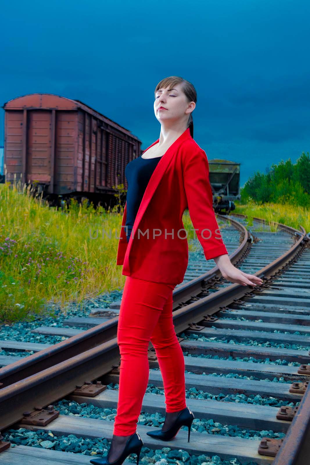 Woman on the rails. In a red trouser suit, the eyes are closed. by Essffes