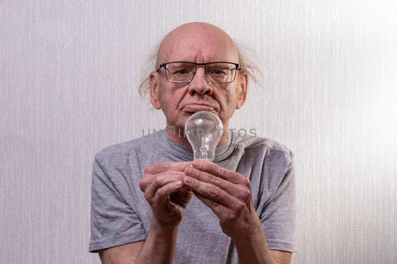 Old man with light bulb. Portrait. incandescent in old hands. Idea. by Essffes