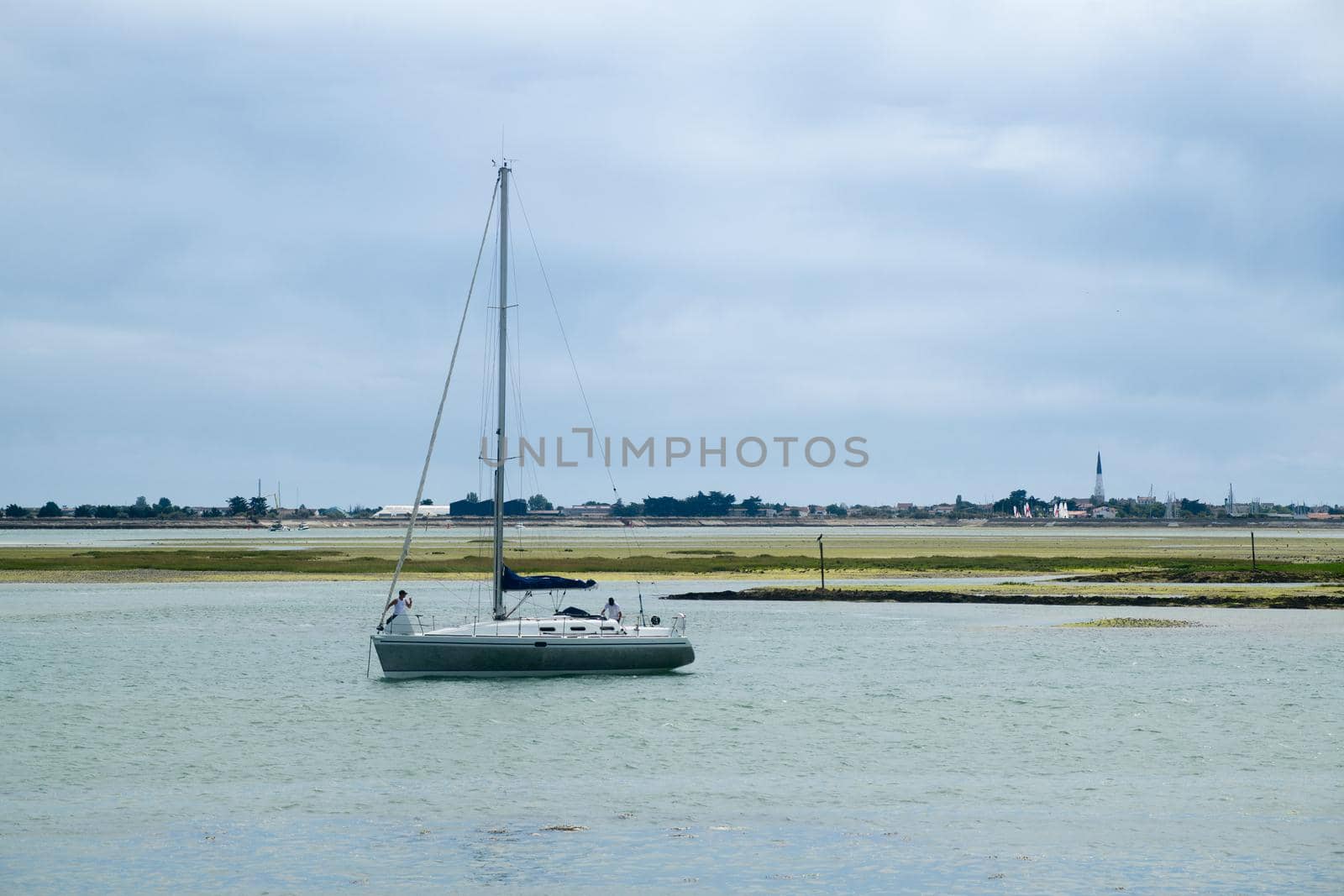 view from the beach of la patache on the preparingof  a boat for sailing with the church of Ars-En-Re in the background on the isle of ile de Re in France