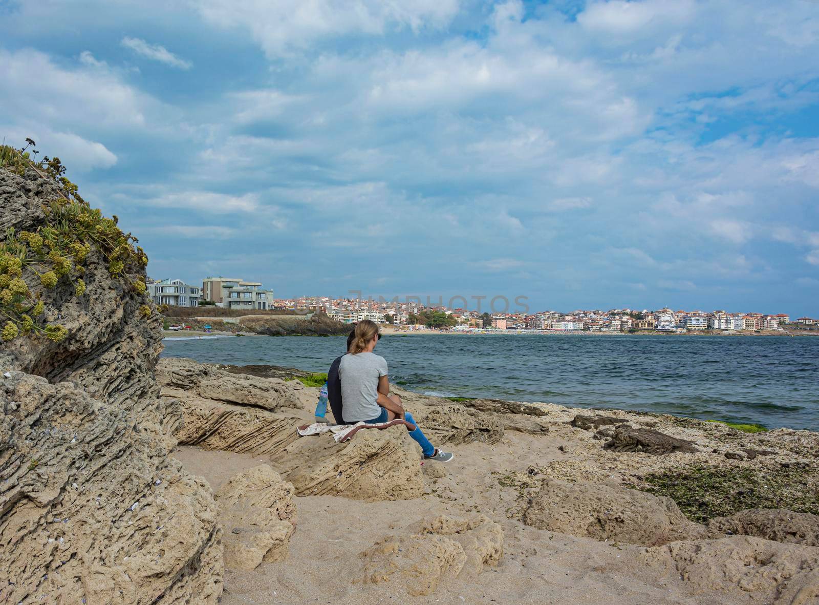 Bulgaria, Sozopol - 2018, 06 September: A girl with a guy sitting on a rocky beach, blurred background. Stock photo.