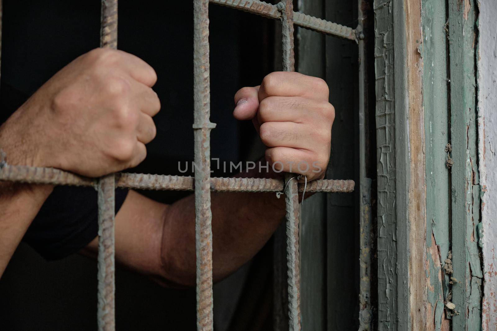 Person's hands holding prison bars by snep_photo