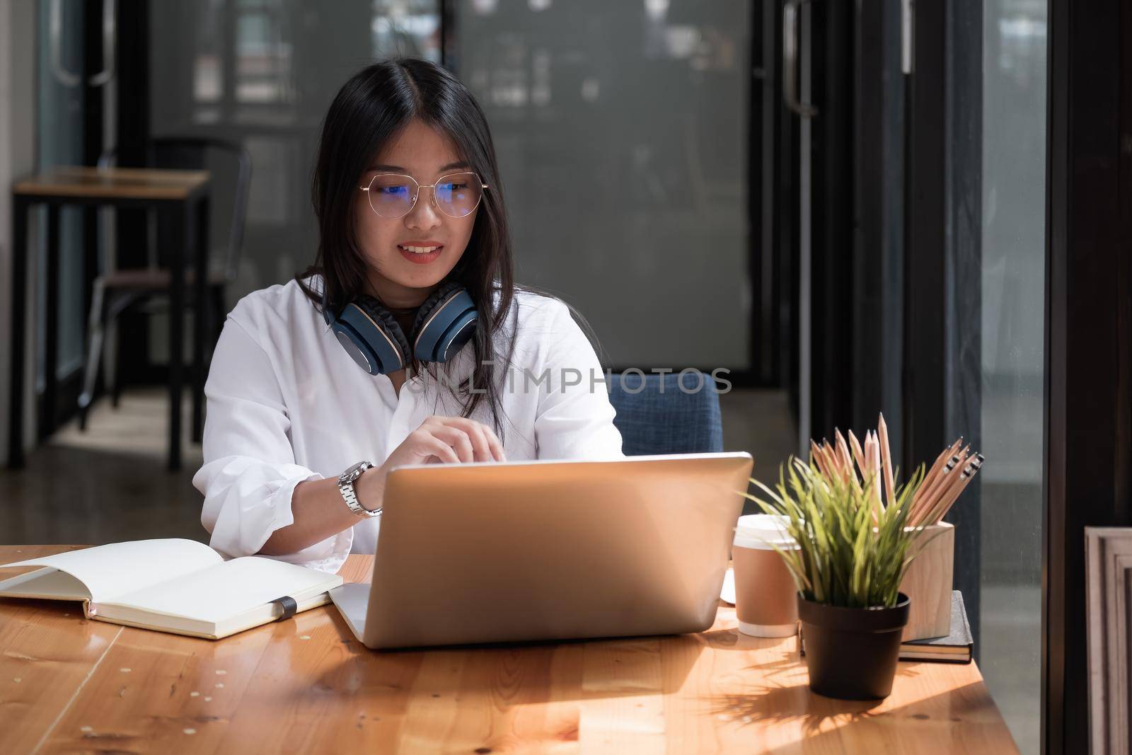 Asian girl with glasses look at laptop while doing homework making video call abroad using internet friend connection, Online learning education concept. by nateemee