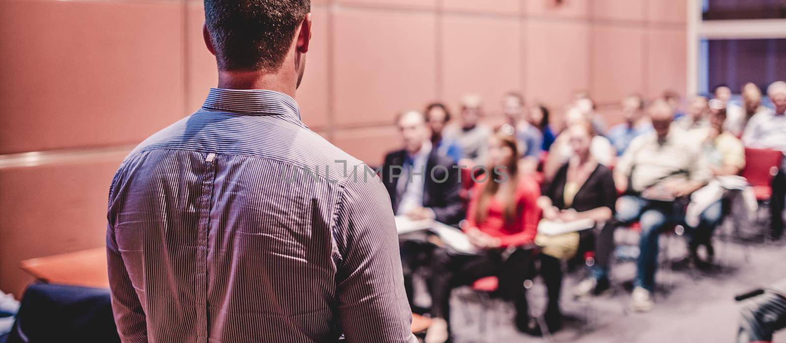 Speaker giving a talk on corporate business conference. Unrecognizable people in audience at conference hall. Business and Entrepreneurship event.