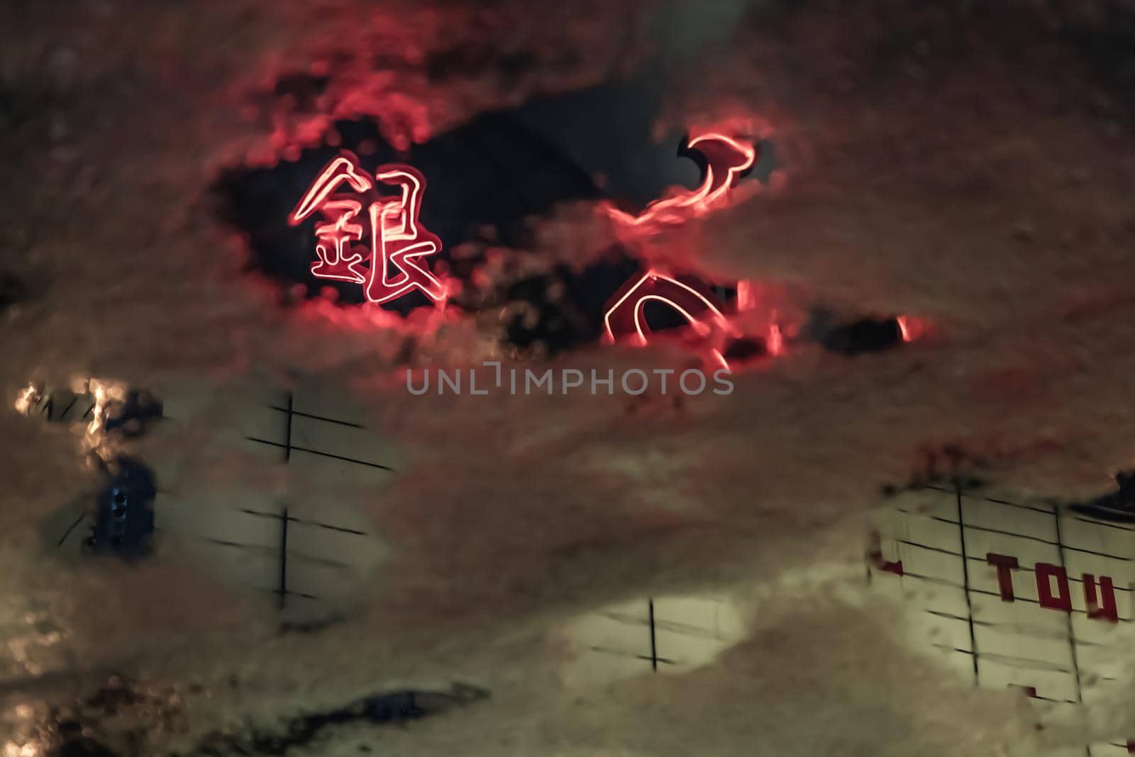 Blurred view of Scala movie theatre at night reflected in water puddle between rain. Thailand.