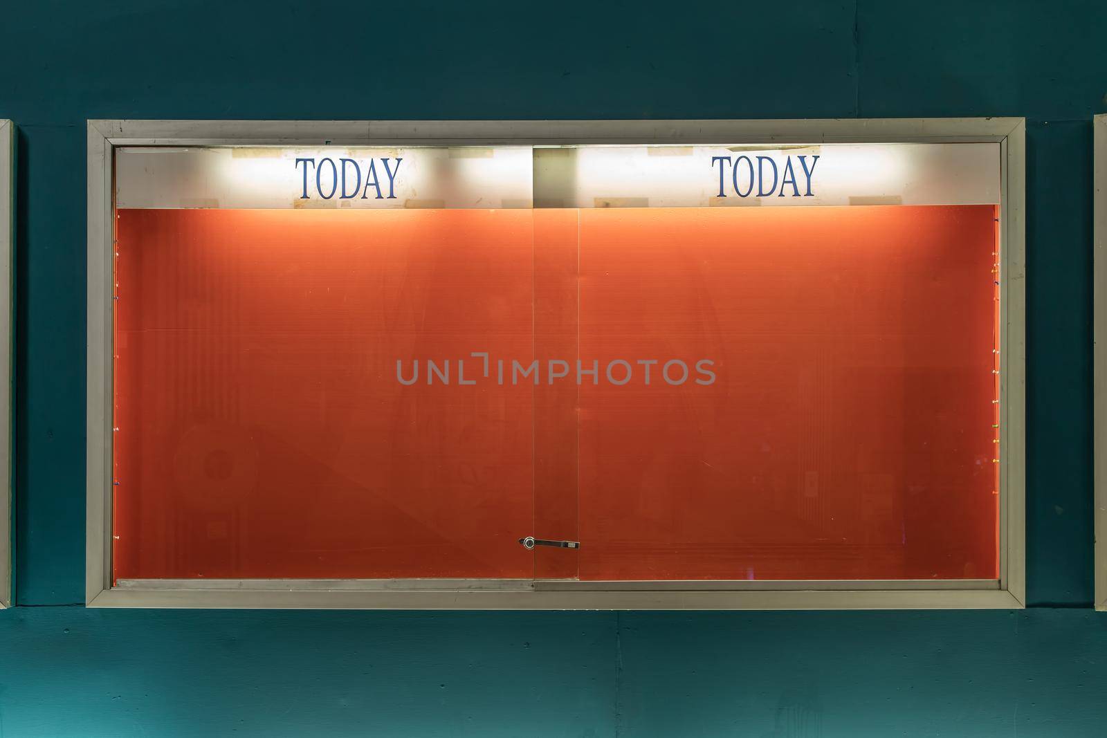 Empty frame of movie posters with spotlight on wall at old standalone movie theatres.