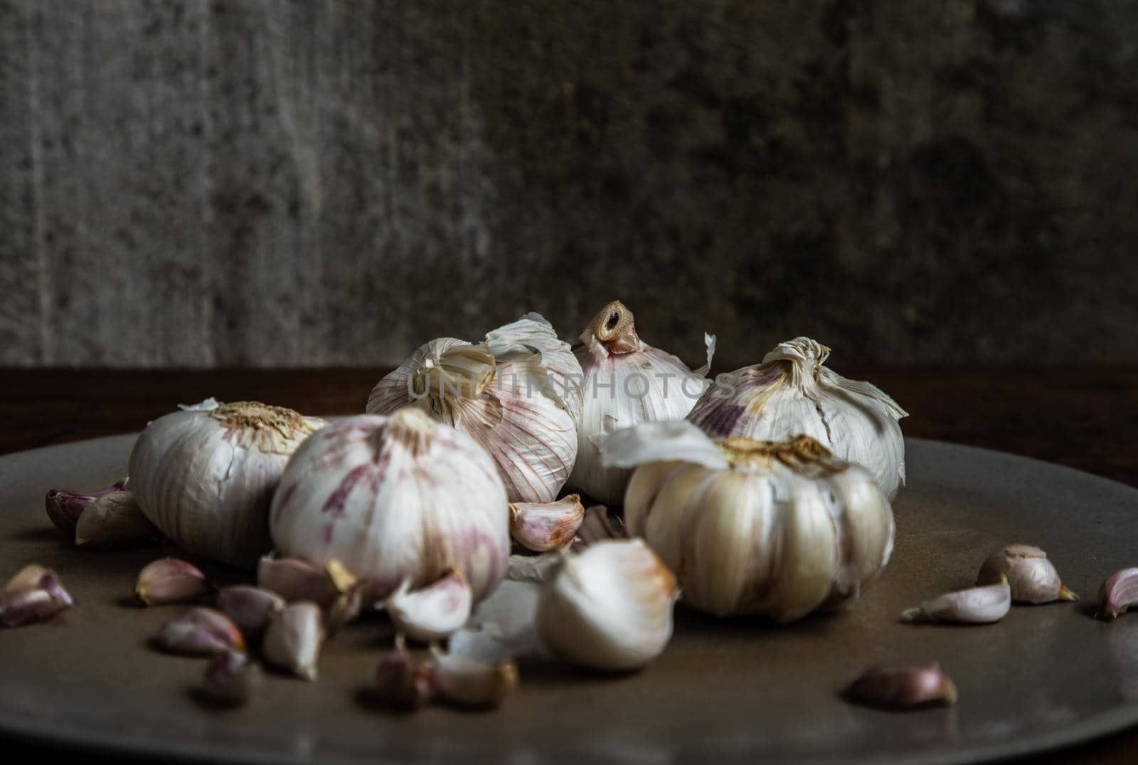 Garlic bulbs and Garlic cloves in Ceramic plate on Wooden rustic table. Copy space Concept of healthy food. No focus, specifically.
