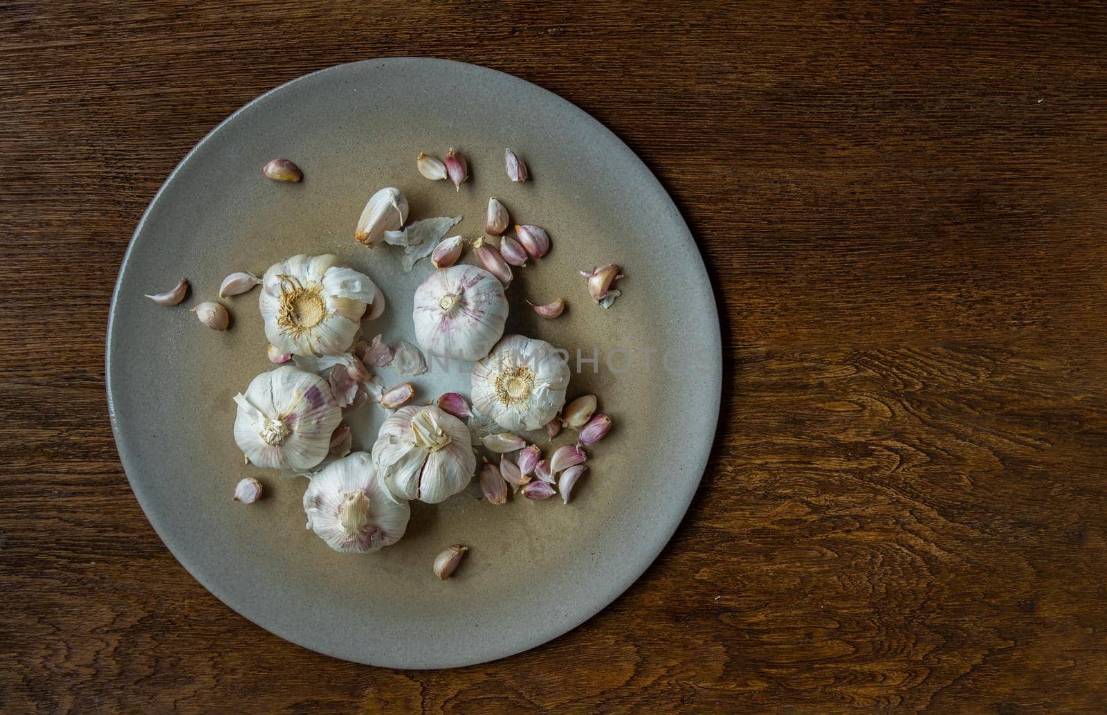 Garlic bulbs and Garlic cloves in Ceramic plate on Wooden rustic table. Copy space Concept of healthy food. Top view, Selective focus.