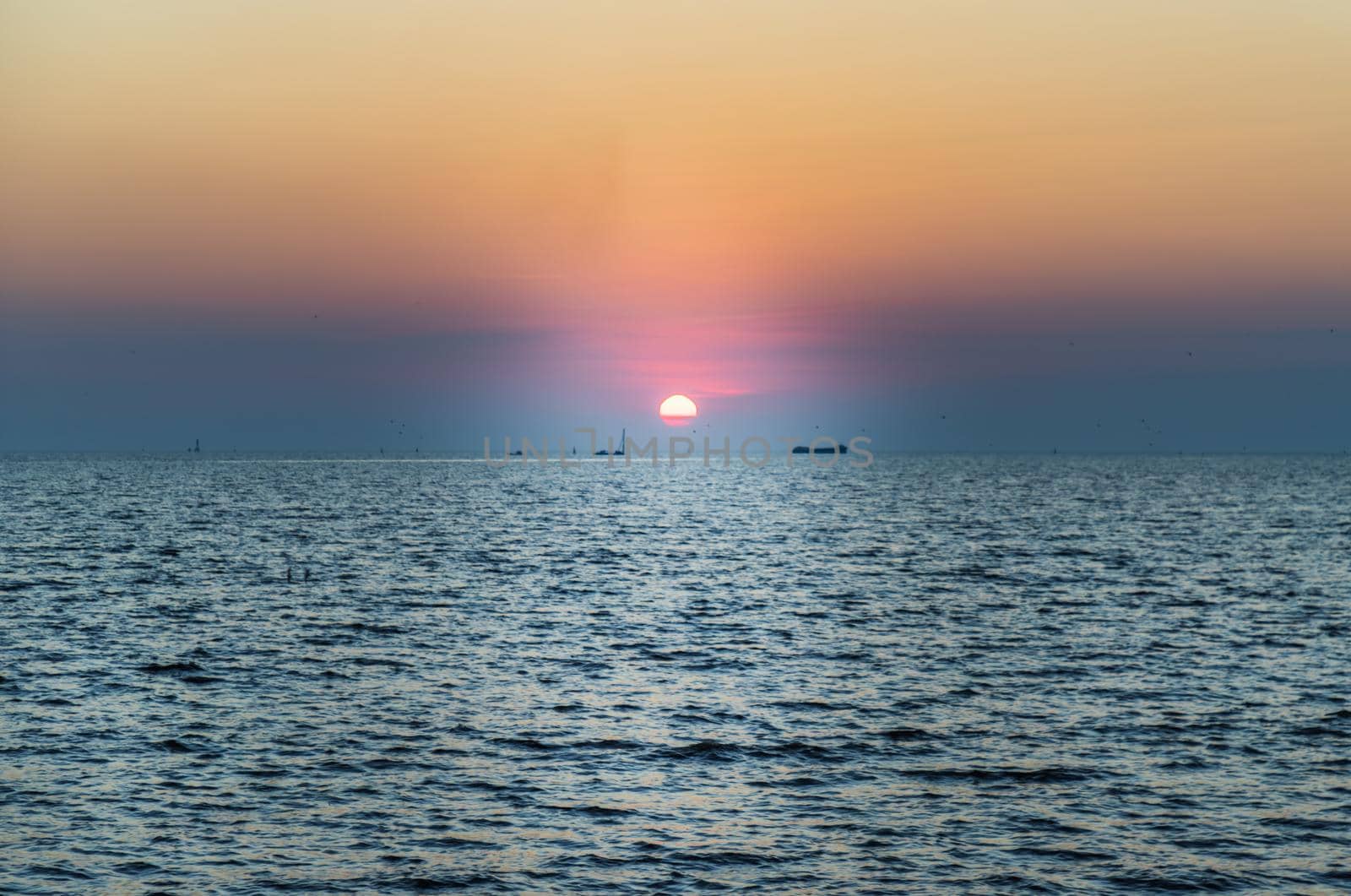 Beautiful sunset over a calm sea with a blue and orange glowing sky. Space for text, Selective focus.